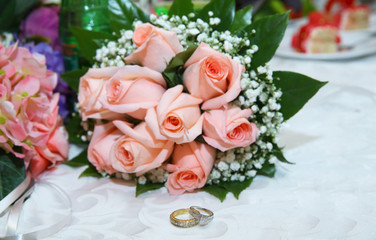 Obraz na płótnie Canvas Gold wedding rings on the pink bouquet of flowers . Stylish pink engagement flower Rings in front of the wedding bouquet .