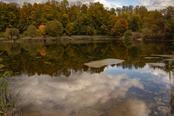 Obraz premium Autumn landscape, colorful forest by the lake with reflection of blue sky on the water