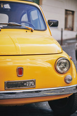 Fototapeta na wymiar Detail view of an old Fiat 500 car typical of Italy in yellow color parked