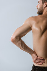 Obraz premium cropped view of shirtless sportsman with lower back pain isolated on grey