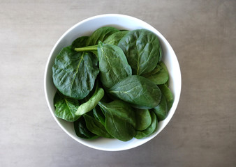 White Bowl with Fresh Baby Spinach on a Gray Background