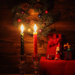 Candles and Santa Claus with Christmas decorations in dark interior