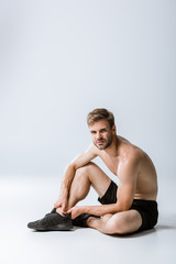 Fototapeta na wymiar shirtless bearded sportsman with ankle pain on grey