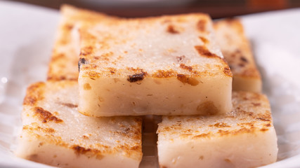 Delicious turnip cake, Chinese traditional local dish radish cake in restaurant with soy sauce and chopsticks, close up, copy space.