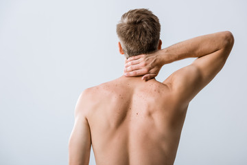 back view of shirtless man with neck pain isolated on grey