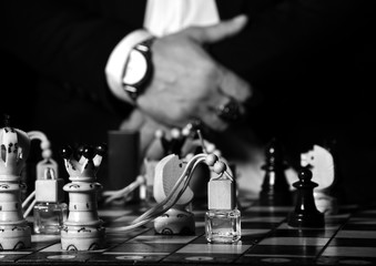 Man in official suit, white shirt and classic watches playing chess with perfume bottles. Black and white 