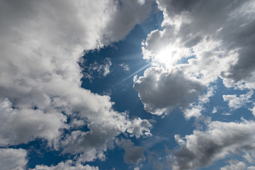 Close-up of a blue sky with clouds and sun rays, backlit, background