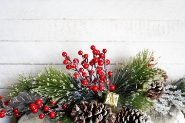 rustic winter decoration with pine, gift and berries on white wooden background, copy space