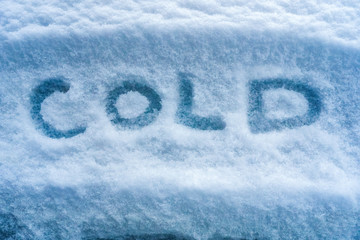 First snow on the ground. White snow background. Word COLD written on the snow. Cold weather....