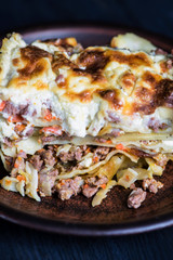 baked lasagna pie with meat and cheese, sauce on a dark background