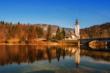 Autumn reflections on lake Bohinj, Julian Alps, the largest permanent lake in Slovenia and the Church of St. John the Baptist.
