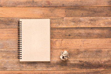 blank craft note book and crumpled paper on wooden table, top view