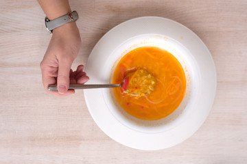 bright orange soup in a white plate.top view