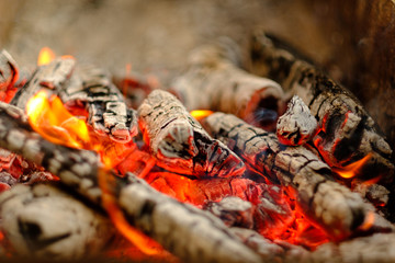 Hot coals and flames in burning campfire