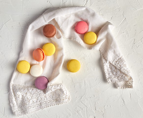 round multi-colored baked macarons with cream on a white towel