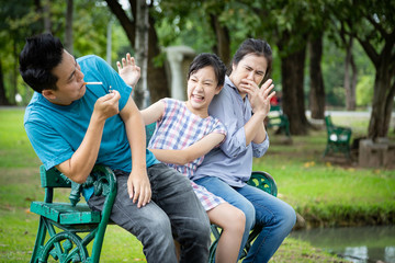 Stop smoking cigarettes,unhealthy ,quit smoking,asian husband holding cigarette in hands near people in family at park,daughter and wife covering face smelling pollution,no smoking,health care concept