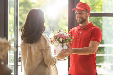 selective focus of happy man in cap giving flowers to woman