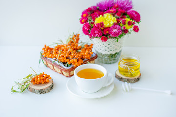 White background, natural lighting. Warm sweet organic tea with sea buckthorn berries, thyme and honey.