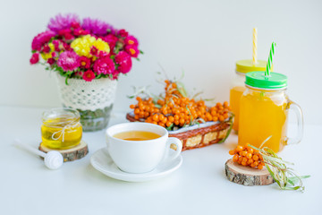 White background, natural lighting. Warm sweet organic tea with sea buckthorn berries, thyme and honey.