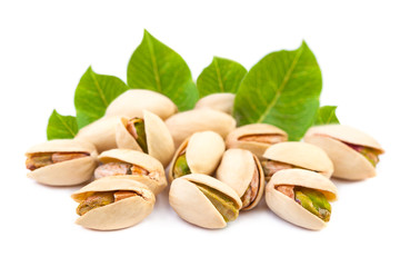 A few Pistachio nuts with leaves on white background