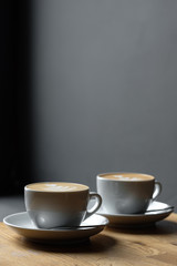 two cups of cappuccino are on the table coffee art