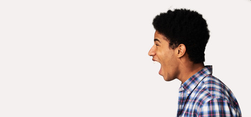 Profile portrait of screaming teen guy, white background © Prostock-studio