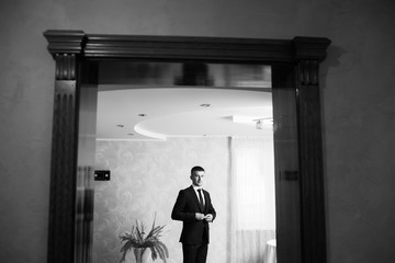 Handsome man in wedding suit smile.   Groom getting ready in the room for wed day. Young groom dressed in his home. Wedding. Details. Black and white