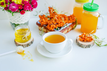 White background, natural lighting. Warm sweet organic tea with sea buckthorn berries, thyme and honey.