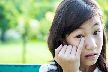 Asian teenager girl painful,sore eyes,touching with finger,hand or rubbing her eye,feeling eyes pain,female patient have dust,insect,foreign bodies,itching in the eye in green nature