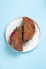 Two pieces of chocolate cake cut in half on a blue background. Minimalism.