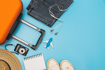Flat lay orange suitcase with traveler accessories on soft blue background. travel, summer and holiday concept
