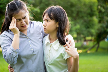 Asian female patient having blood pressure disease,vertigo,dizziness,sick mother migraine headache touch her head with her hands,heat stroke, daughter help,care,support in park,healthcare concept