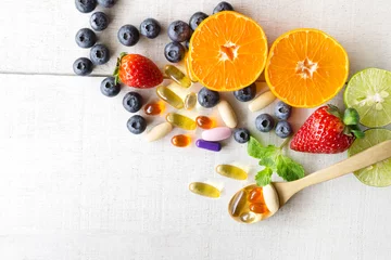 Fotobehang Multivitamins and supplements with fresh and healthy fruits on white wooden background. © Praewpan