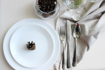Christmas table setting, white plates and appliances on the festive table with a tablecloth of ecological products. without plastic.