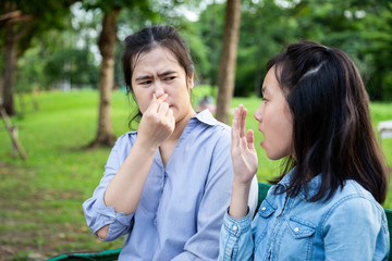 Obraz premium Asian daughter child girl checking breath teenager girl horrible bad breath,foul mouth,mother closing her nose,very smell,female people holding breath with fingers on nose feeling stinks, halitosis 