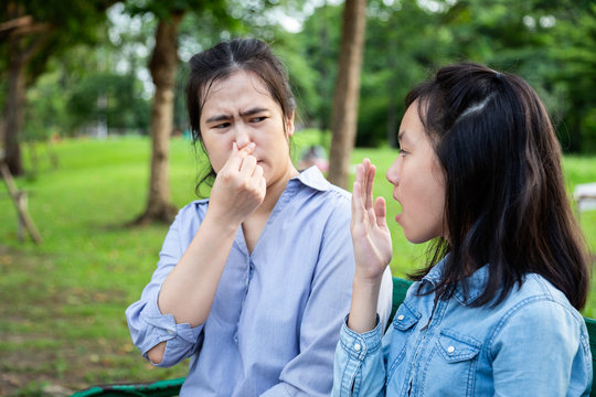 Asian daughter child girl checking breath teenager girl horrible bad breath,foul mouth,mother closing her nose,very  smell,female people holding breath with fingers on nose feeling stinks, halitosis 