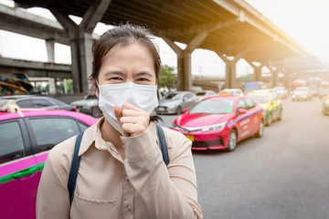 Asian woman suffer from cough with face mask protection,sick people wearing medical mask because of air pollution in the city streetl,air polluted,concept of pollution,dust allergies,health care