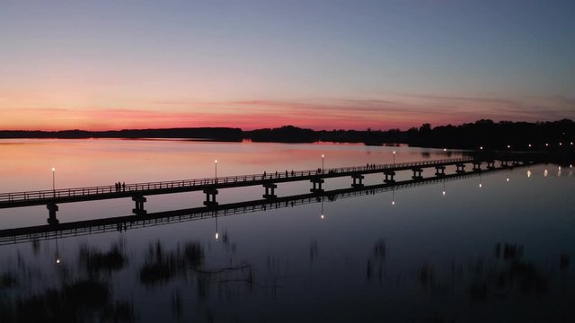 Drone Flight at Sunset by the lake Sirvena in Birzai - the longest wooden bridge in Lithuania.The bridge is located in Regional Park, connecting Birzai with Astravas Manor on the northern edge of the