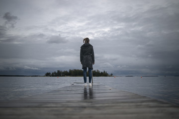 A woman stands on the pier in cold cloudy weather