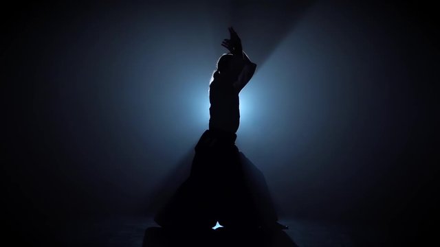 Silhouette martial arts Aikido master on spotlight background.