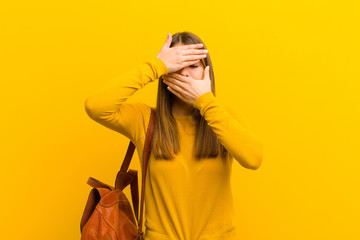 young pretty woman covering face with both hands saying no to the camera! refusing pictures or...