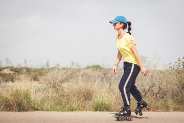 Fototapeta premium Woman skating on a lonely road in the desert
