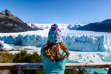 A female tourist is standing in front of Perito Moreno Glacier, Los Glaciares National Park in...