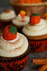 Homemade pumpkin Cupcakes with cream cheese frosting with halloween candy topping, selective focus