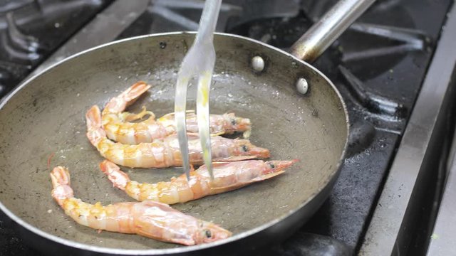 Chef sta cucinando i gamberoni nella padella in un ristorante stellato