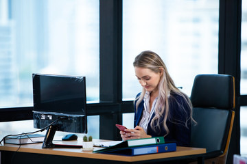 business woman wearing suit looking smartphone a in hands and sitting on workplace
