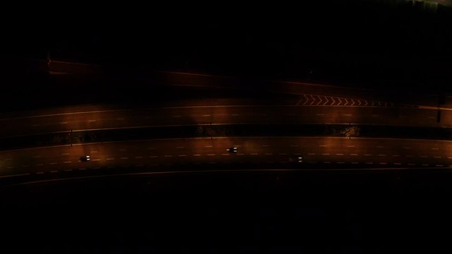 Night traffic on illuminated road junction. Cars driving on elevated road, overpass and city highway.