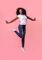 Playful african girl having fun over pink studio background