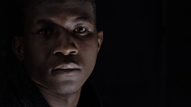 Sad proud Black African Migrant looking At Camera In The Darkness