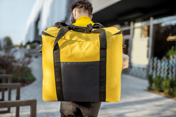 Delivery Man standing with yellow thermo backpack for food delivery with empty space to copy paste...